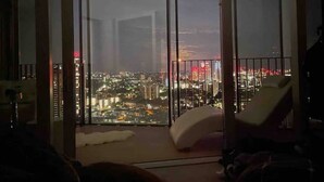 A high-rise room with a large window overlooking a cityscape at night. - Stunning city penthouse with 360-degree skyline views (London)