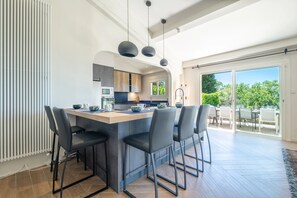 A modern kitchen with a central island, bar stools, and pendant lighting. - Magnificent Provençal-style estate (Châteauneuf-Grasse)