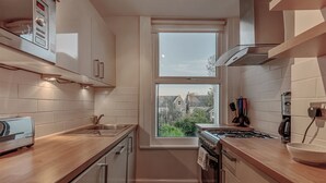Una cocina compacta con ventana, tostadora, estufa y pileta.