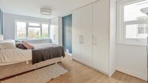 Un dormitorio con cama, armario, ventana y radiador.
