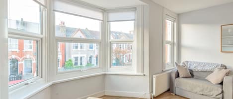 A room with large windows, a grey sofa, and a radiator.