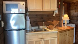 Une cuisine compacte équipée d’un réfrigérateur en acier inoxydable, de meubles de rangement en bois, d’un four à micro-ondes et d’une cuisinière.
