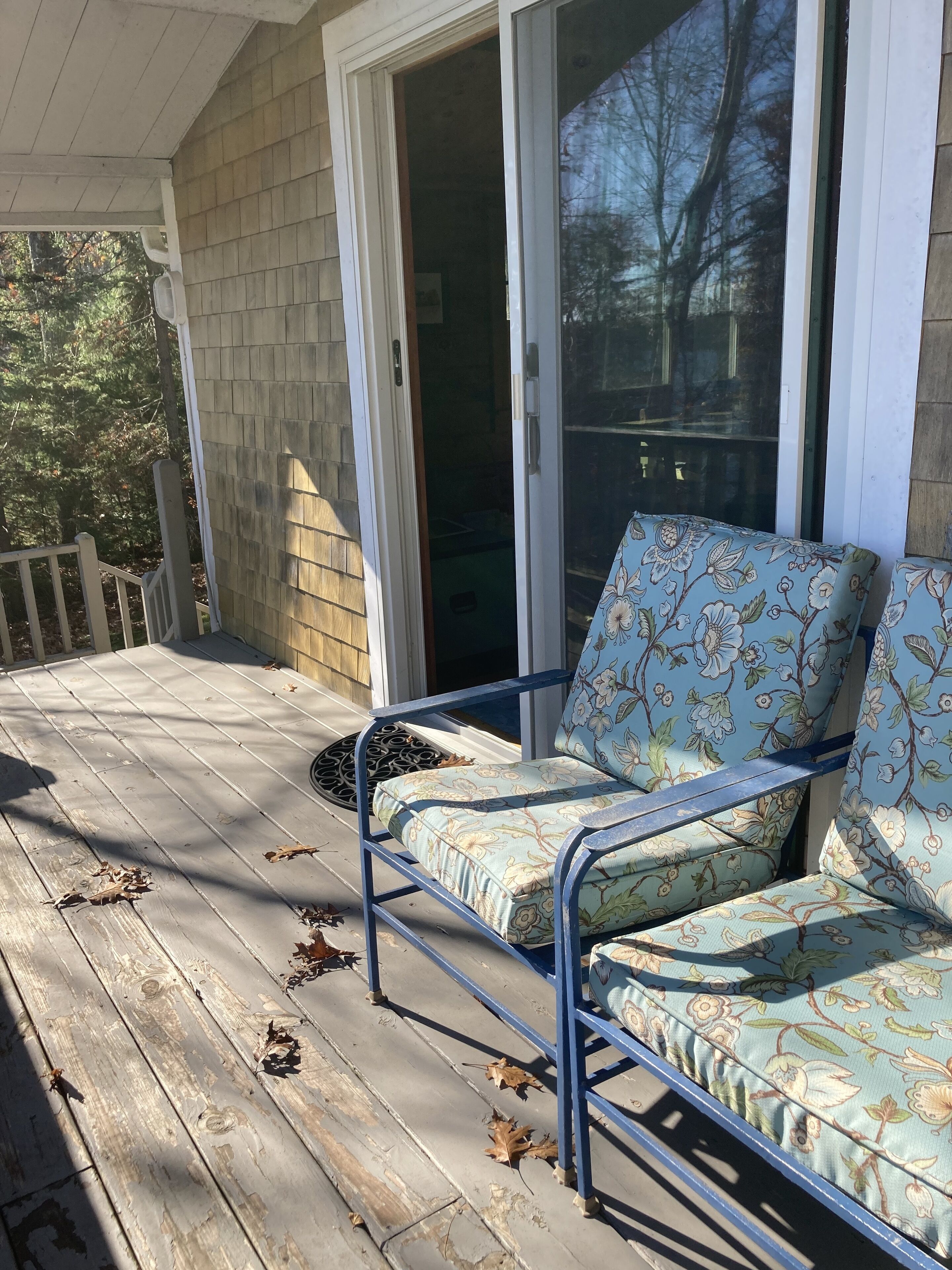 A porch with a blue metal chair and a glass door leading inside.