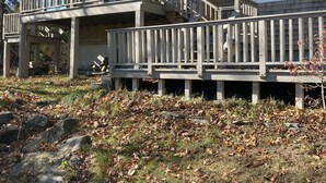 Une maison à deux étages avec une terrasse en bois et un escalier menant à l’étage supérieur.