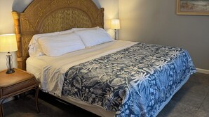 Un dormitorio con cama, mesita de noche, ventilador de techo y lámpara de pared.
