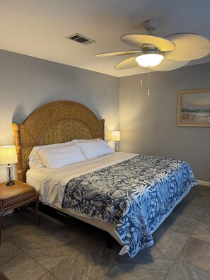 A bedroom with a bed, a nightstand, a ceiling fan, and a wall-mounted lamp. - Secluded Waterfront Home on the Bay (Pensacola)