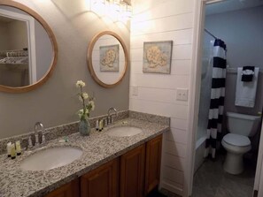 A bathroom with two sinks, a mirror, and a shower curtain. - Tubbies on the Bay (Pensacola)
