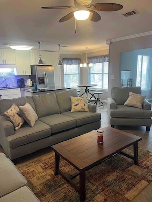 A living room with a sofa, armchair, coffee table, and a ceiling fan. - Tubbies on the Bay (Pensacola)