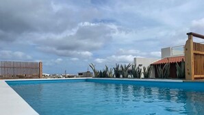 Una piscina con valla de madera y plantas tropicales.