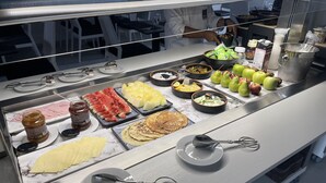Un bufé con diversos alimentos, entre ellos frutas, pasteles y salsas.