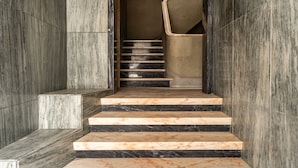Un escalier en marbre, dont les marches alternent entre le noir et le beige, mène à un palier.