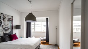 Une chambre à coucher moderne avec un grand lit, une lampe sur pied et un tableau au mur.