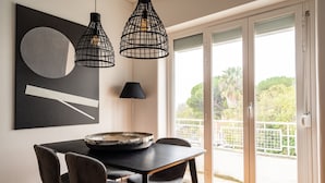 Un espace repas comprenant une table, des chaises, une lampe noire et un grand tableau abstrait.