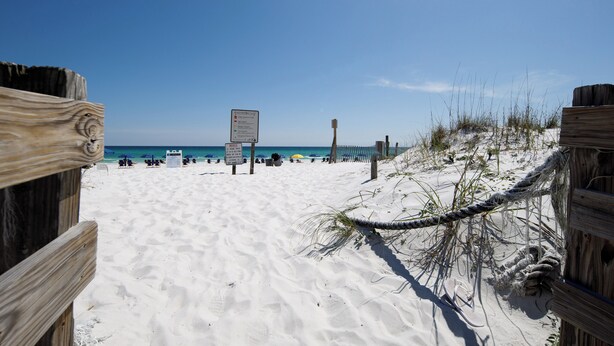 A sandy beach with wooden fences and a signboard.