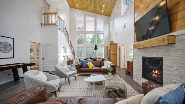 A spacious living room with a fireplace, a pool table, and a large window overlooking greenery. - NEW Spectacular Modern Retreat -The Fika House-Lux (Broken Bow)