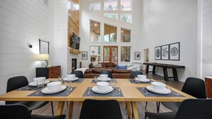 A dining area with a long table set for a meal, a fireplace, a sofa, and a pool table. - NEW Spectacular Modern Retreat -The Fika House-Lux (Broken Bow)