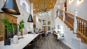A spacious kitchen with a long island, wooden staircase, and large windows. - NEW Spectacular Modern Retreat -The Fika House-Lux (Broken Bow)