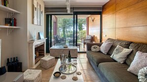 Ein modernes Wohnzimmer mit einer Couch, einem Couchtisch und einem Kamin. Bücherregale und Blick ins Freie.