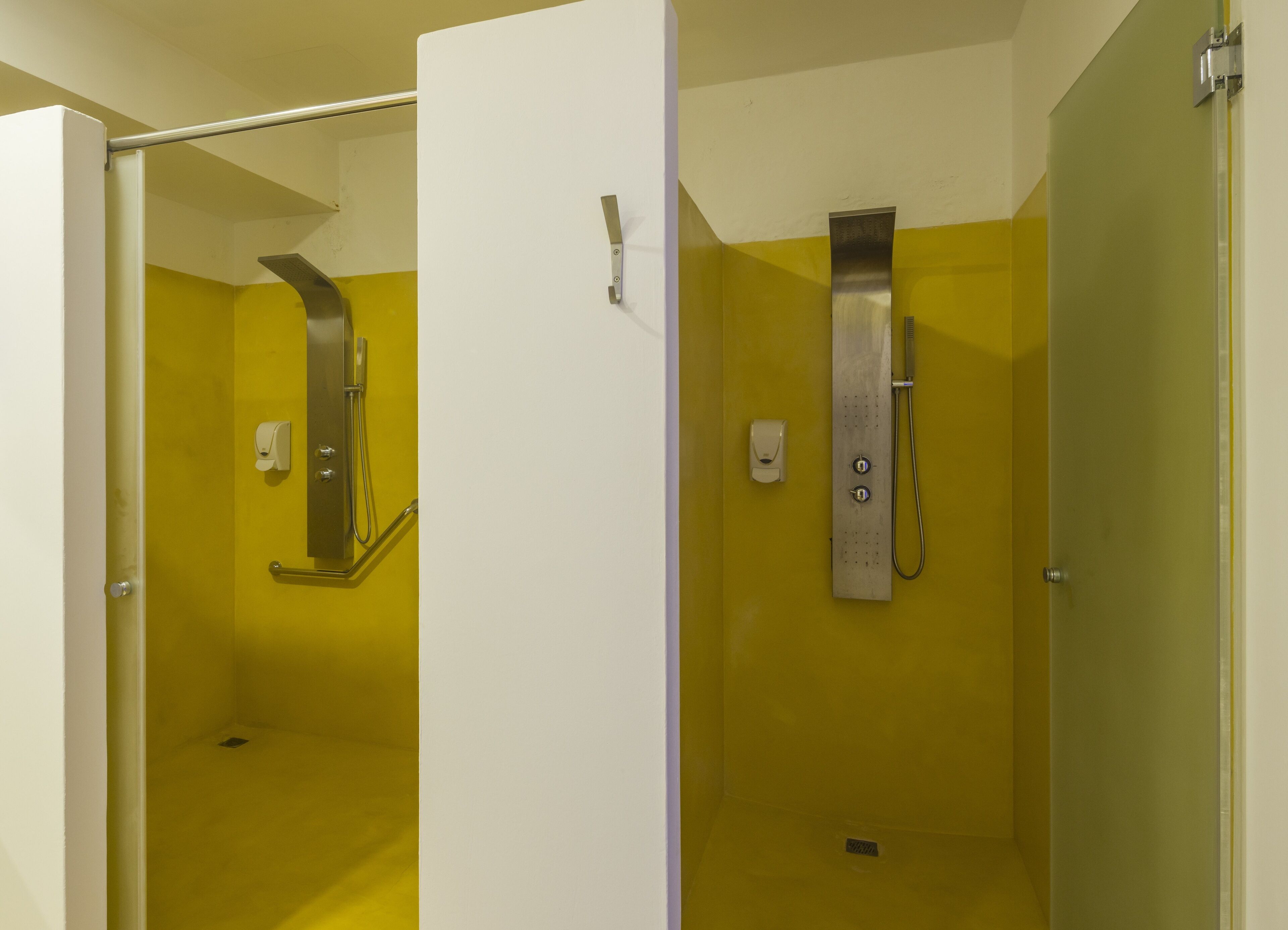 A restroom with yellow walls, a white door, and a glass partition.