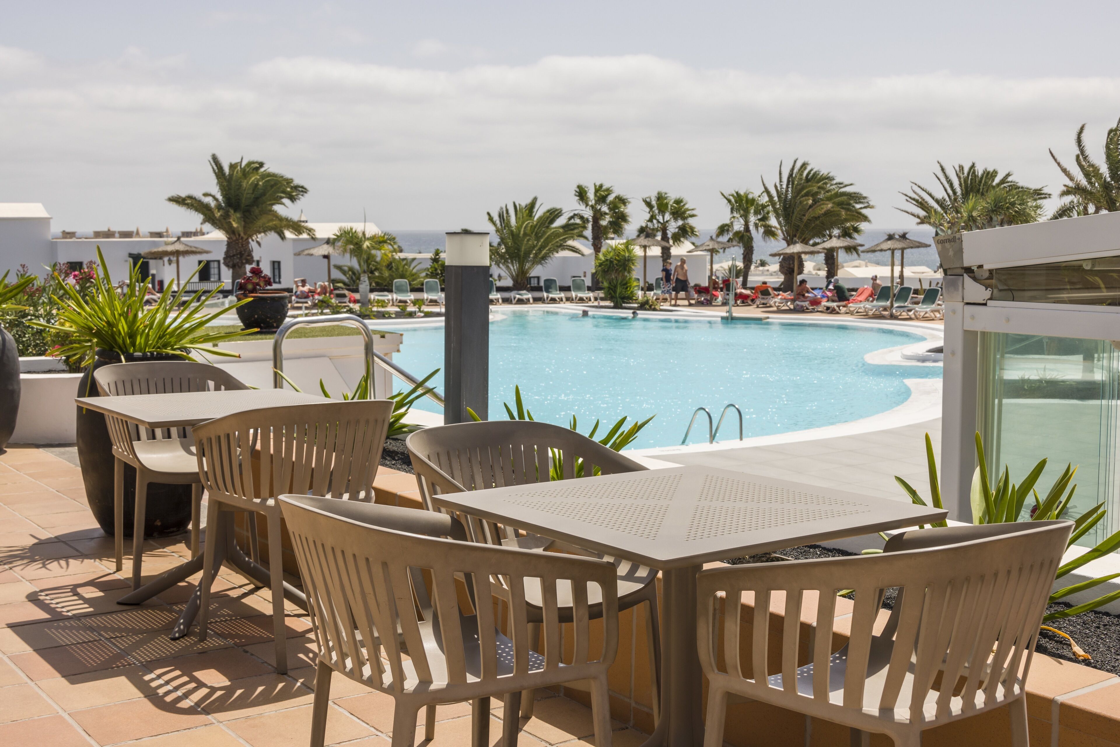 Zona de piscina con sillones y mesas, con vista al agua.