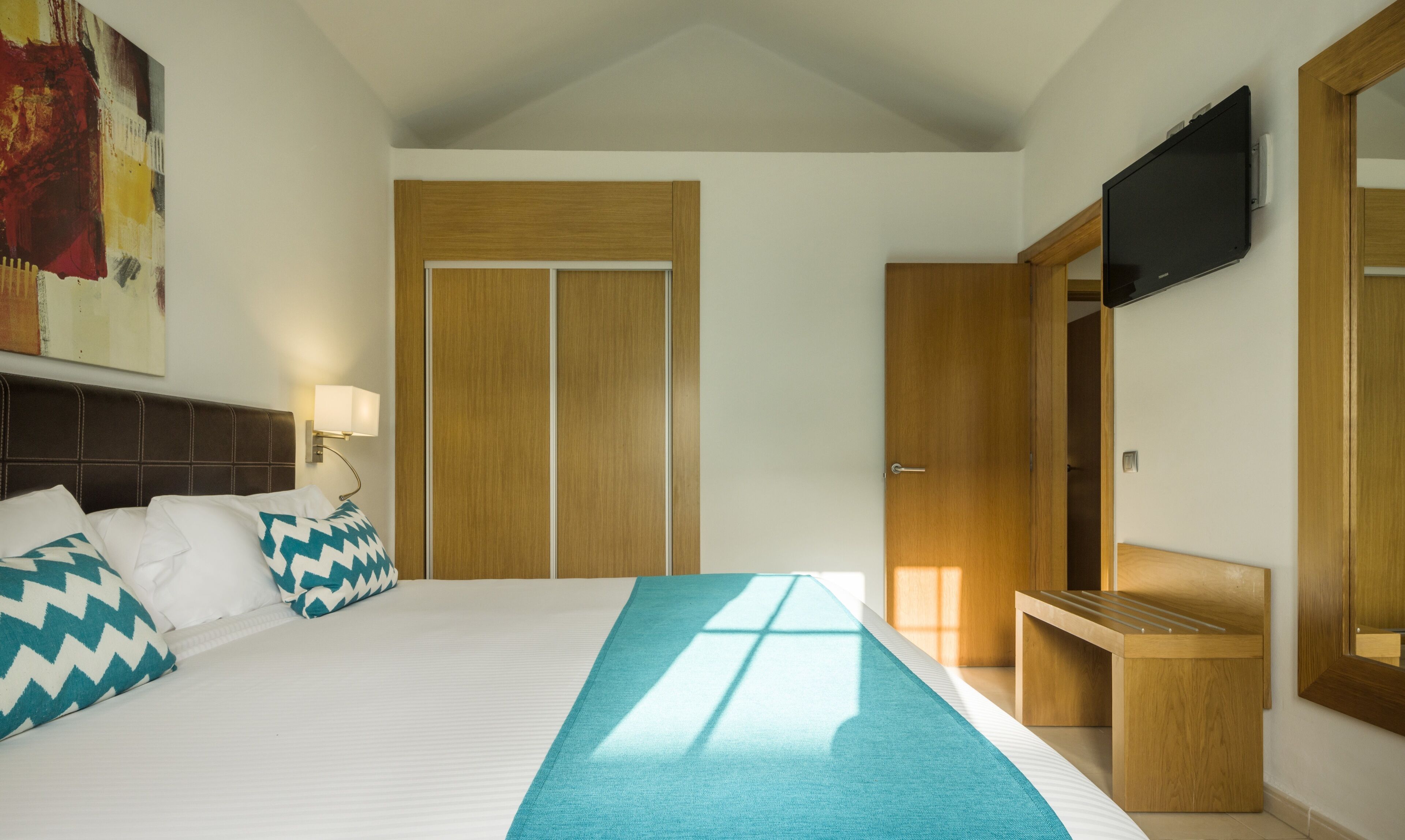 Une chambre d’hôtel équipée d’un lit, d’un bureau, d’une télévision et d’une armoire.