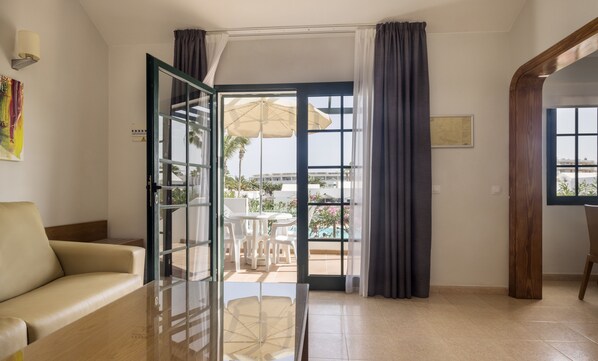 Quarto de hotel com porta de vidro que dá para uma área externa com guarda-sóis e cadeiras.