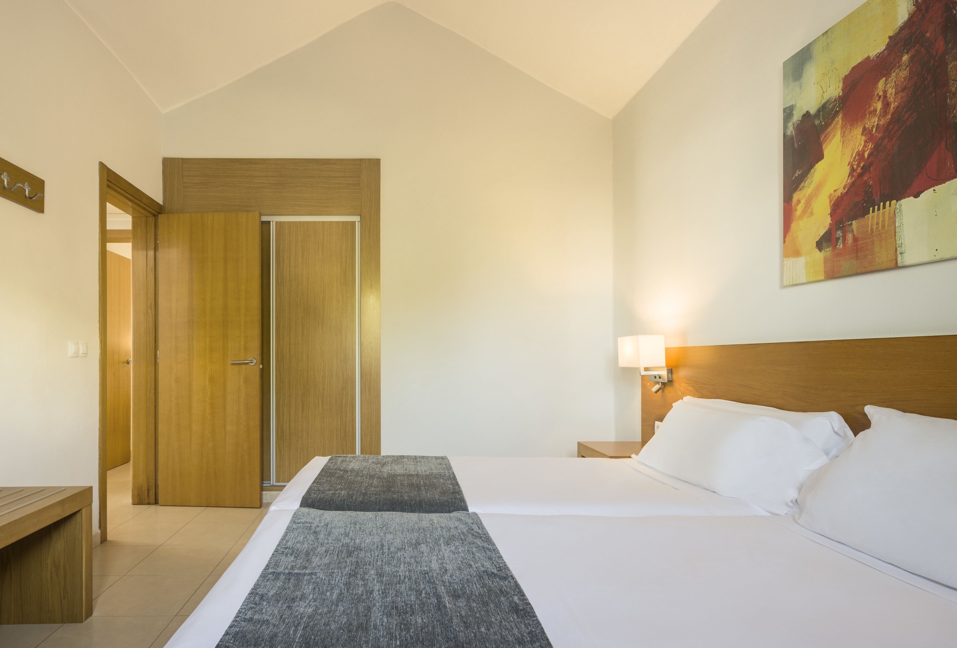 Una habitación de hotel con cama, mesita de noche y un cuadro en la pared.