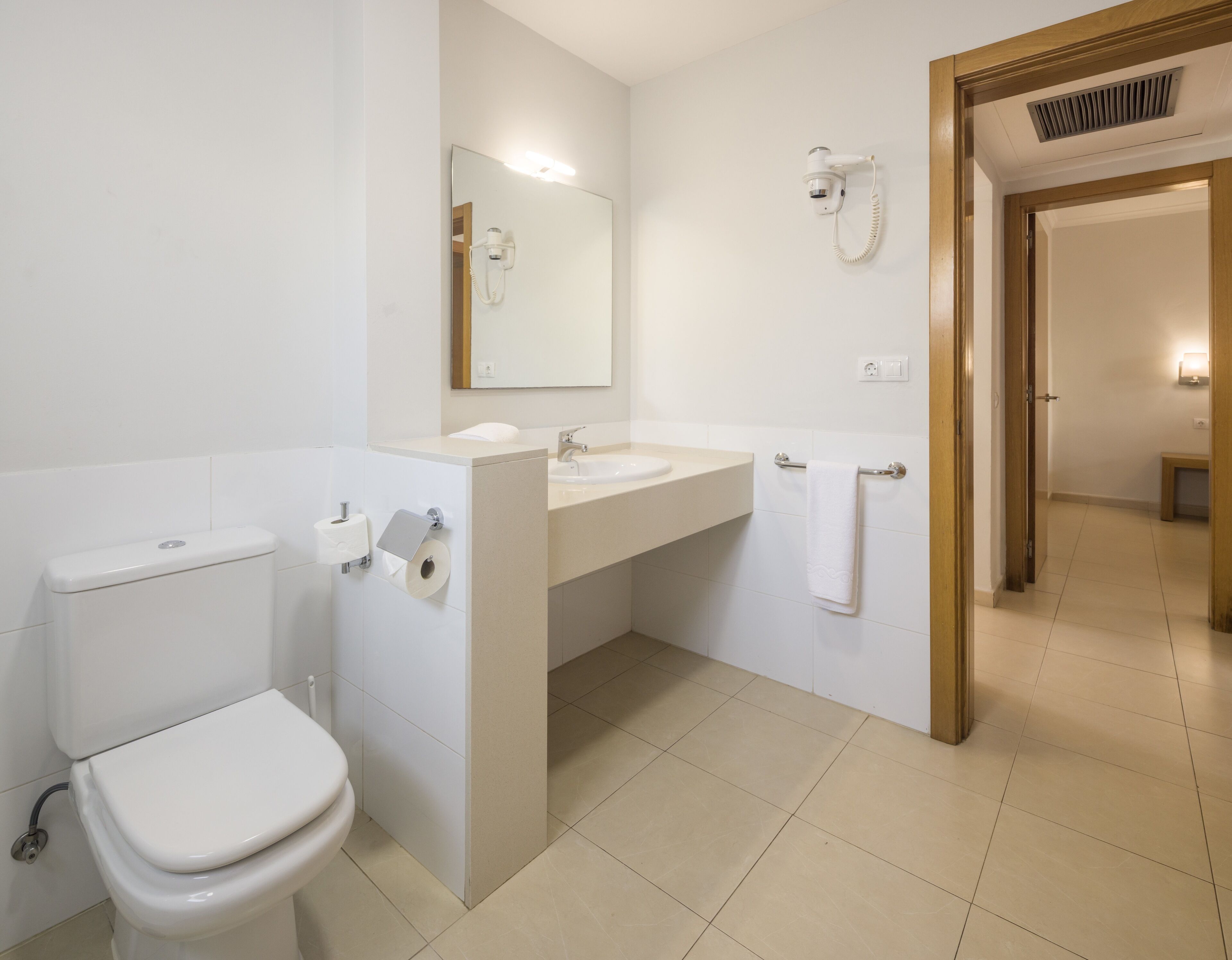 A modern bathroom with a toilet, sink, and mirror.