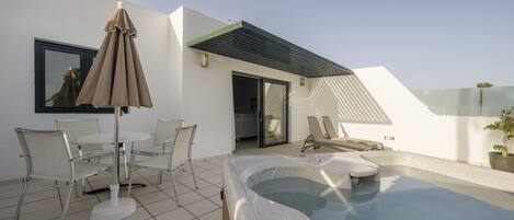A modern outdoor area with a pool, lounge chairs, and a table with chairs.