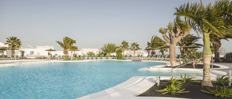A pool area with lounge chairs and palm trees.