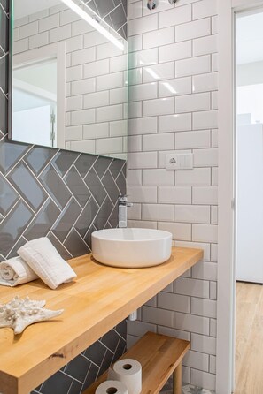 Un baño con lavamanos blanco, encimera de madera y espejo.