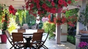 Une terrasse extérieure avec un sol en pierre, une table ronde et quatre chaises.