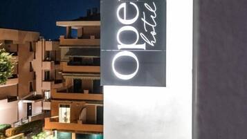 A modern hotel sign with the name "Open Hotel" illuminated at night.