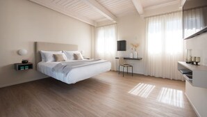 Un dormitorio moderno con una cama grande, un escritorio y un televisor montado en la pared.