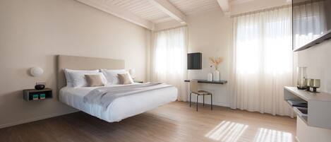 Un dormitorio moderno con una cama grande, un escritorio y un televisor montado en la pared.