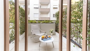 Un balcón con una mesa lista para el desayuno, una silla y una planta en maceta.