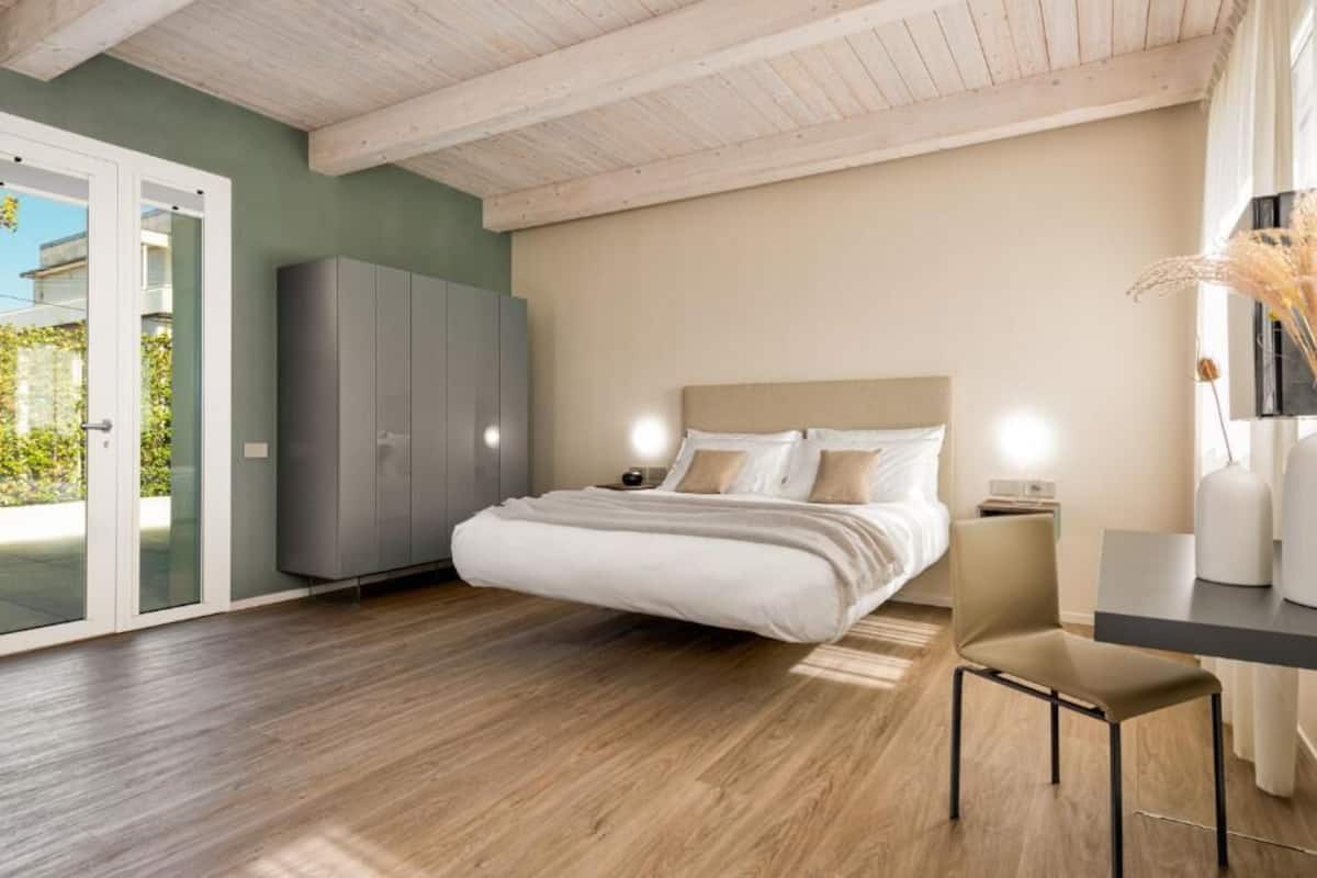 A bedroom with a bed, a desk, and a wardrobe.