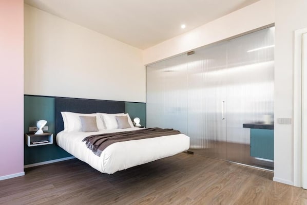 A modern bedroom with a large bed, a nightstand, and a sliding glass door leading to a bathroom. - Open Hotel (Rimini)