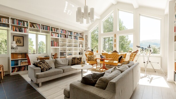 A spacious living room with a large bookshelf, a comfortable sofa, and a dining area with a table and chairs. - Edsåsgården (Undersaker)