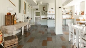 A spacious kitchen with white cabinetry, a wooden table, and a checkered floor pattern. - Edsåsgården (Undersaker)