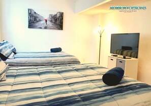 Une chambre avec deux lits, une télévision et un tableau au mur.