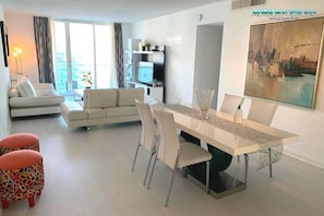 Uma sala de estar moderna com uma mesa de jantar, sofá e pufes coloridos.