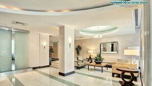 A spacious lobby with a marble floor, a reception desk, seating area, and a large mirror. - The Tides on the Beach by Aurich Designs (Hollywood)
