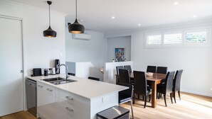 A modern kitchen with a central island, a dining area with a wooden table and chairs, and pendant lighting.