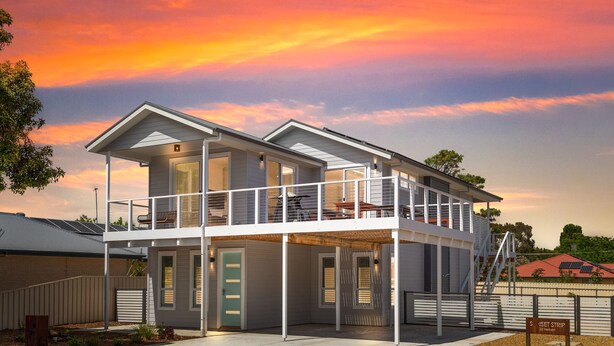 A two-story house with a balcony, a garage, and a driveway.