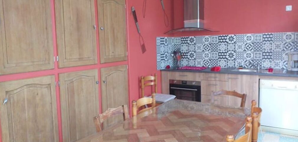 Una cocina con armarios de madera, salpicadero de azulejos y una mesa de comedor con sillas.
