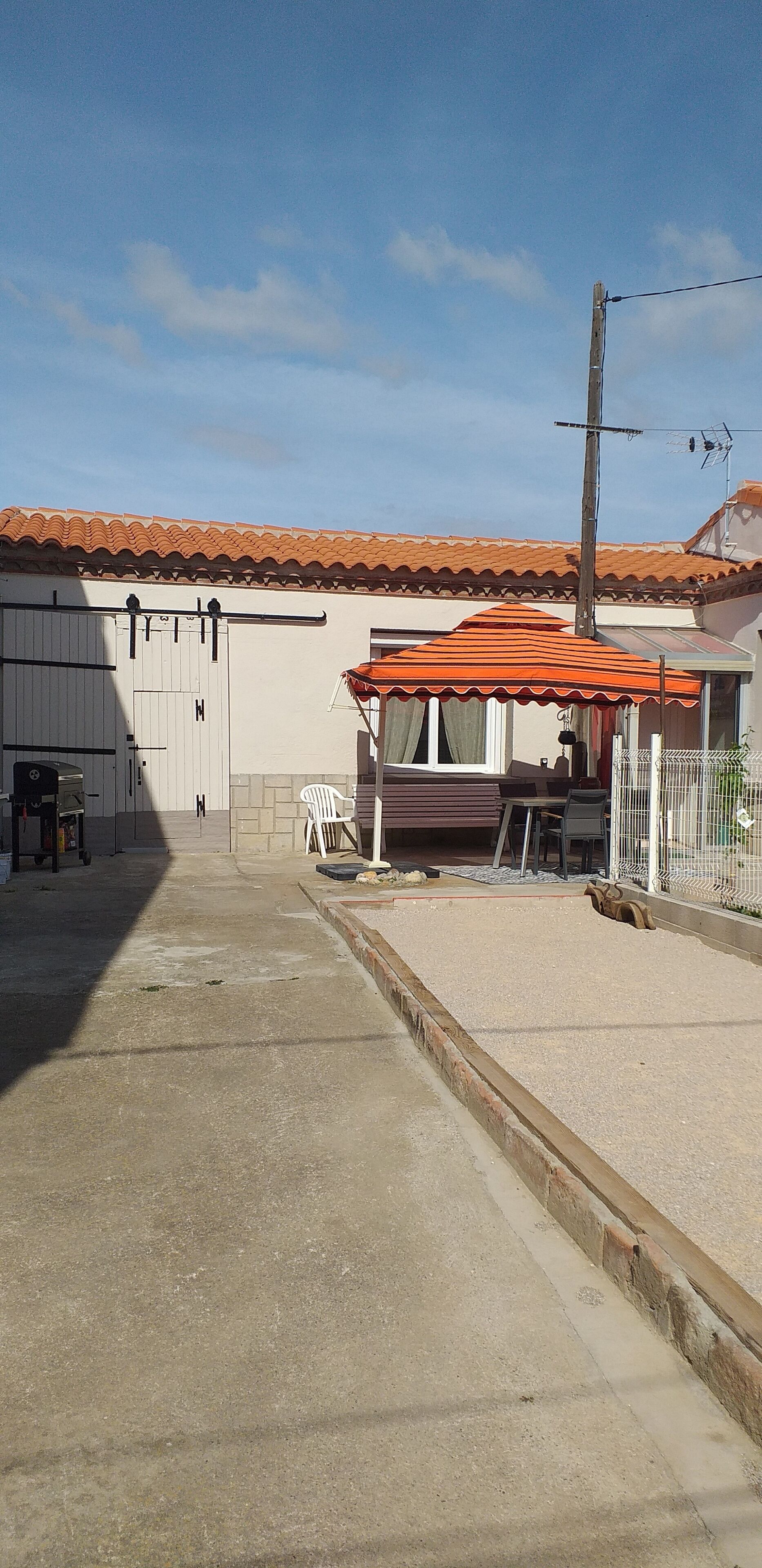 A courtyard with a building, a covered seating area, and a fenced enclosure.