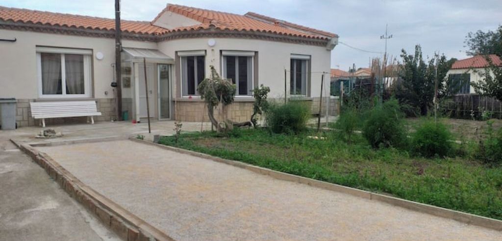 Una casa de dos pisos con techo de tejas, un porche delantero y un pequeño jardín.