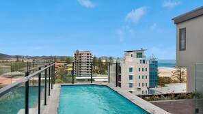 Un edificio moderno con piscina y vistas a la playa y al océano.