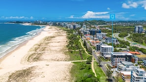 Eine Luftaufnahme einer Küstenstadt mit Strand, Wohngebäuden und einer Autobahn.